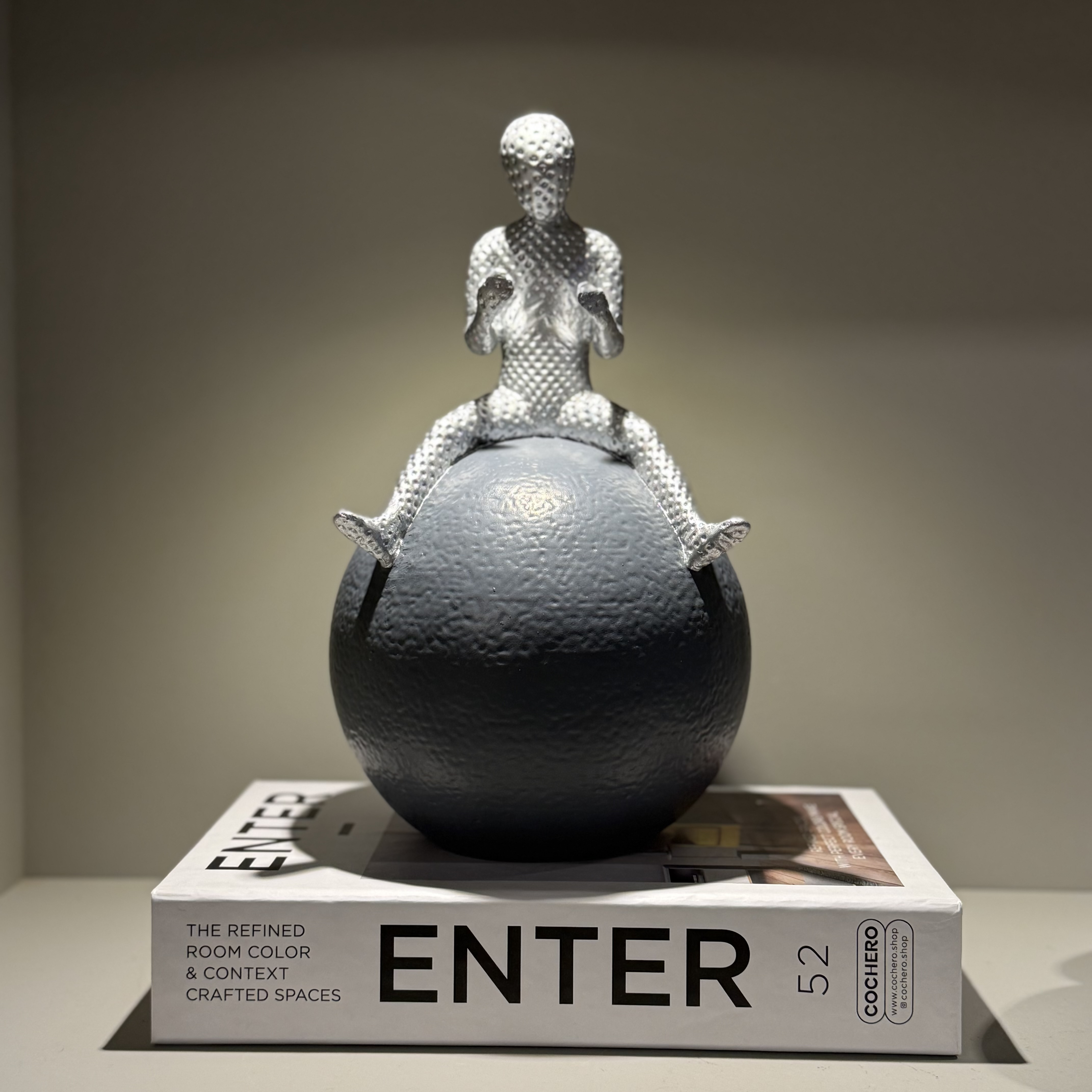 مجسمه مرد نشسته روی گوی